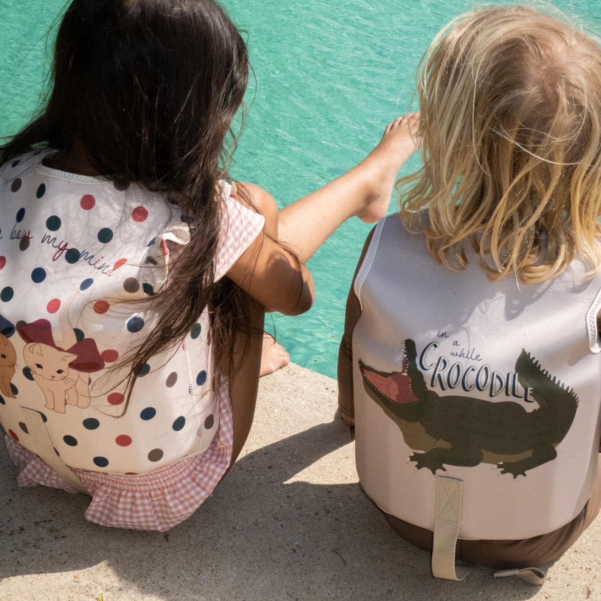 Konges Sløjd Schwimmweste mit Kirsch-Print aus weichem Neopren, getragen von einem Kind am Wasser für sicheren und stilvollen Badespaß.